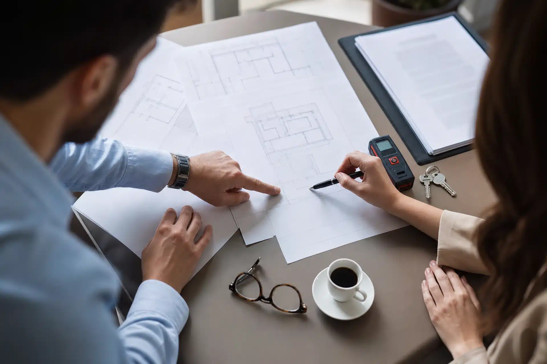 Agente immobiliare e cliente esaminano planimetrie catastali e documenti